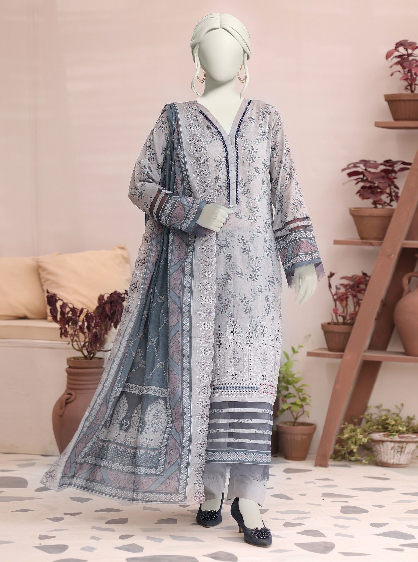 Mannequin wearing a long, patterned dress in a room with plants and a sofa.