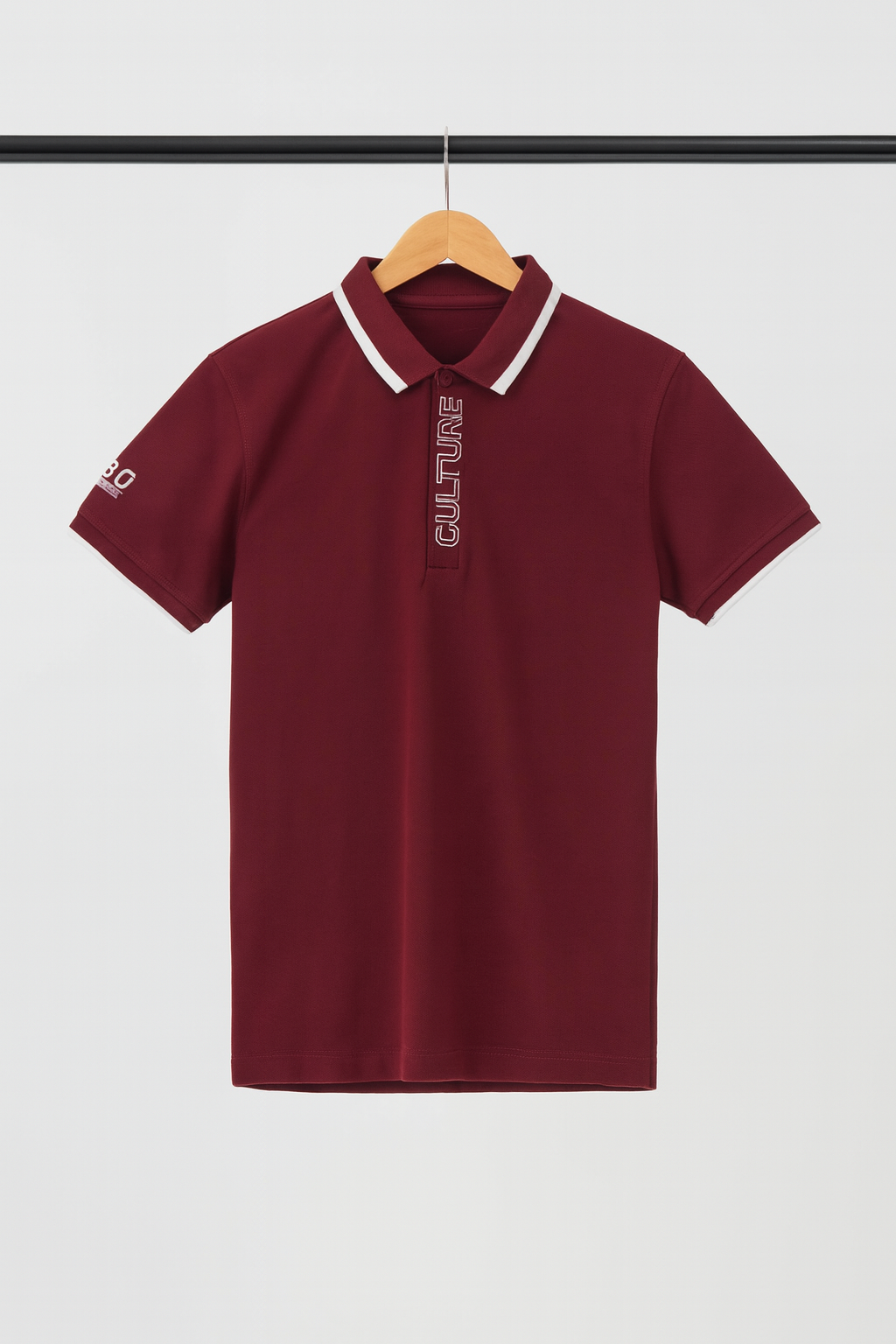Maroon polo shirt with white collar on a hanger against a light gray background