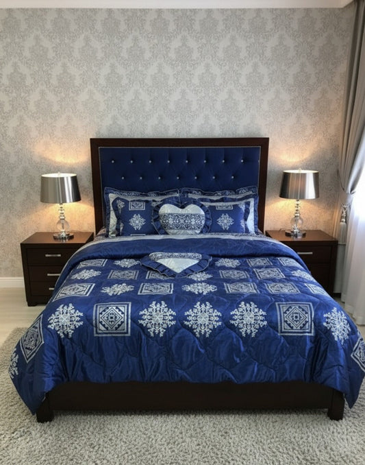 Blue patterned comforter on a bed with matching pillows in a bedroom setting.