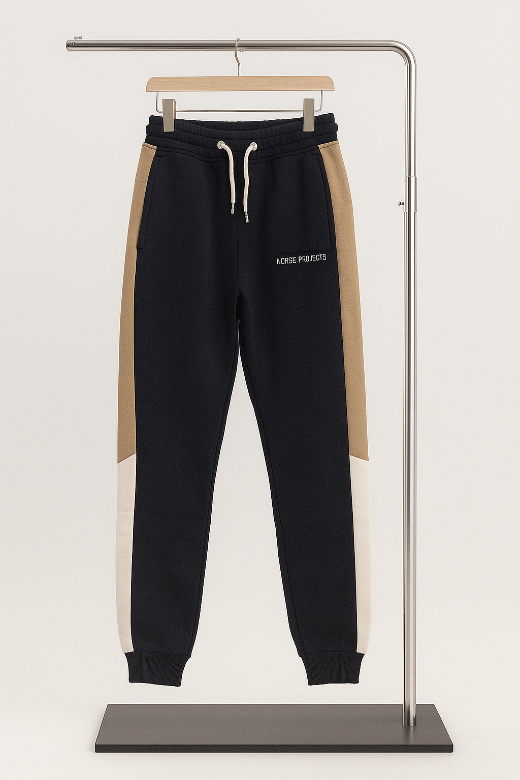 Navy and beige jogger pants on a hanger against a white background