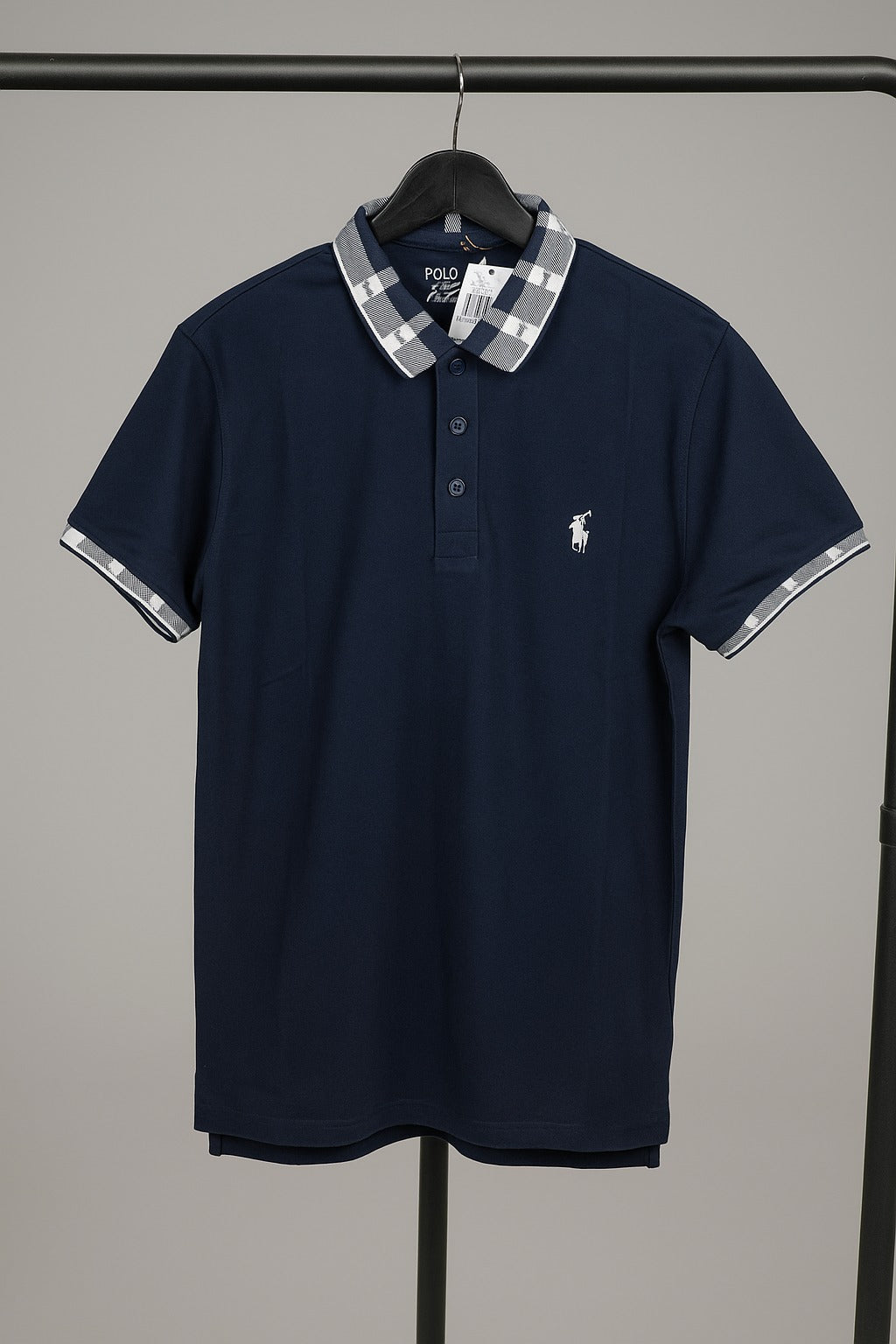 Navy blue polo shirt with plaid collar on a hanger against a gray background