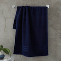Navy blue towel hanging on a rack against a concrete wall.