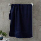 Navy blue towel hanging on a rack against a concrete wall.