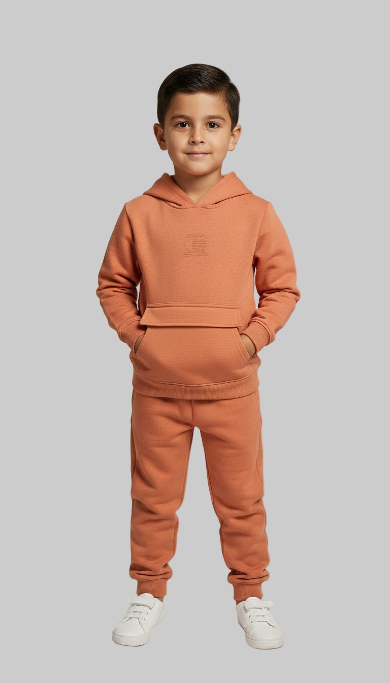 Child wearing a Orange tracksuit on a gray background