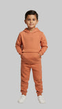 Child wearing a Orange tracksuit on a gray background