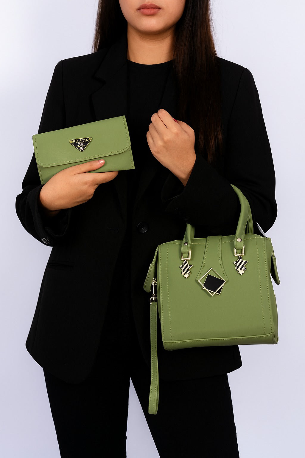 Person holding a green handbag and clutch against a white background