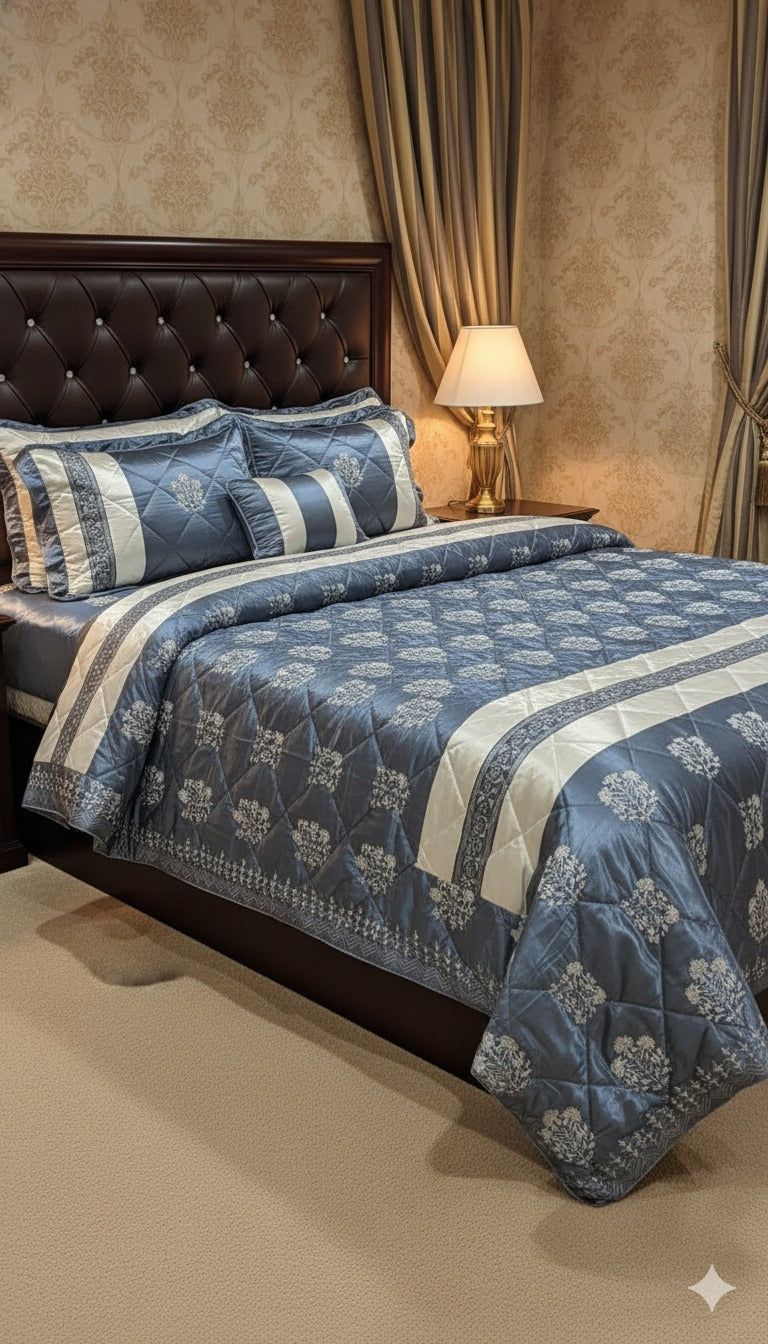 Blue and white floral patterned comforter set on a bed with matching pillows, against a beige wall.