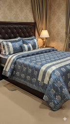Blue and white floral patterned comforter set on a bed with matching pillows, against a beige wall.