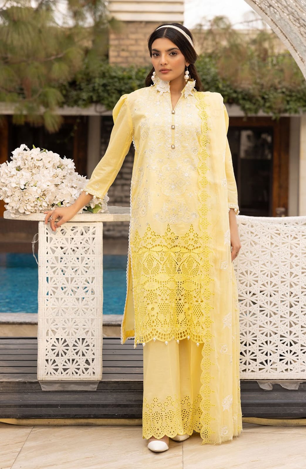 Woman wearing a yellow embroidered outfit standing outdoors.