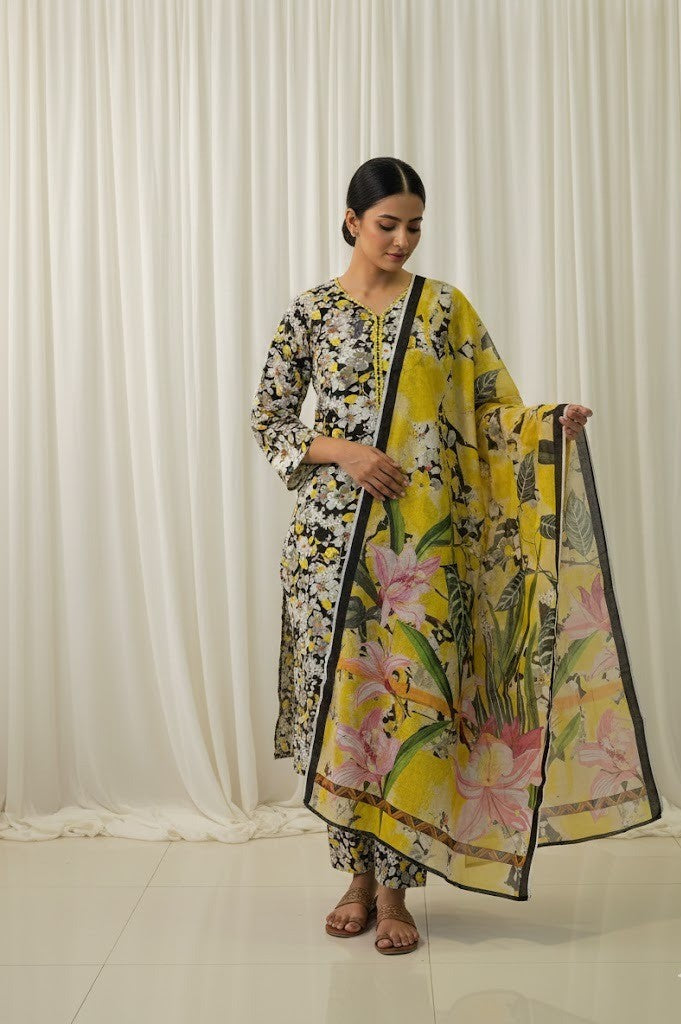 Woman holding a floral yellow dupatta against a white curtain background