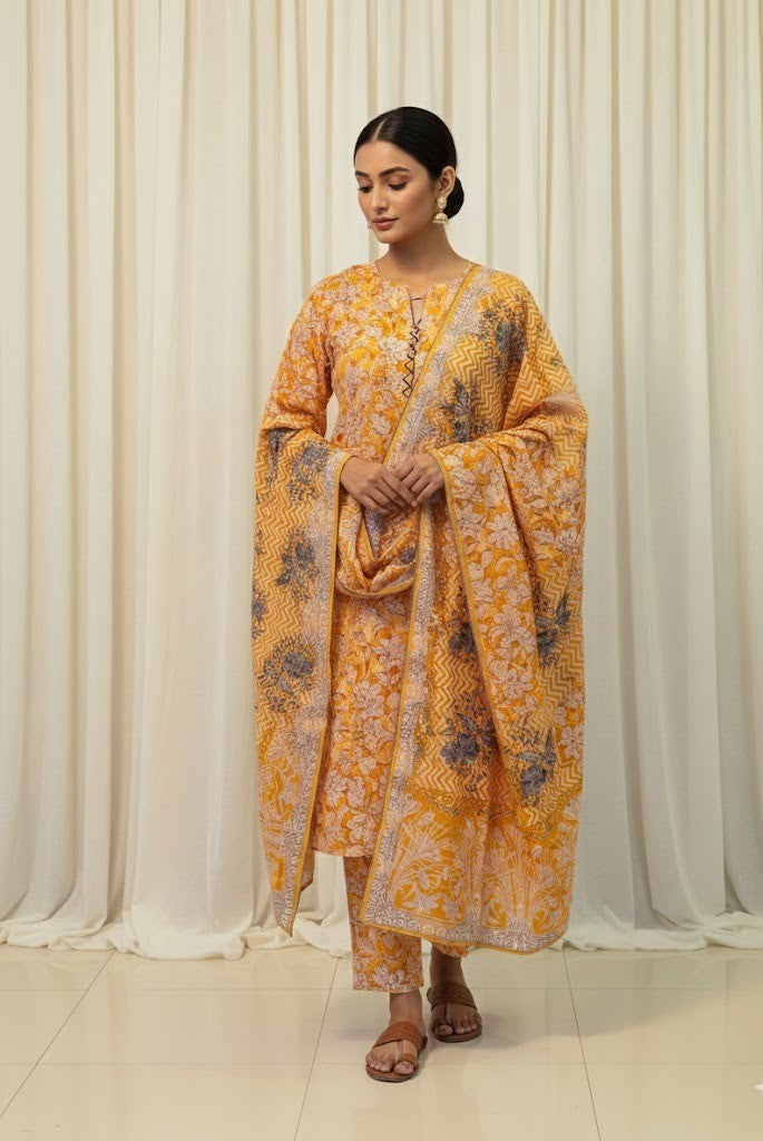 Woman wearing a yellow floral outfit against a white curtain background