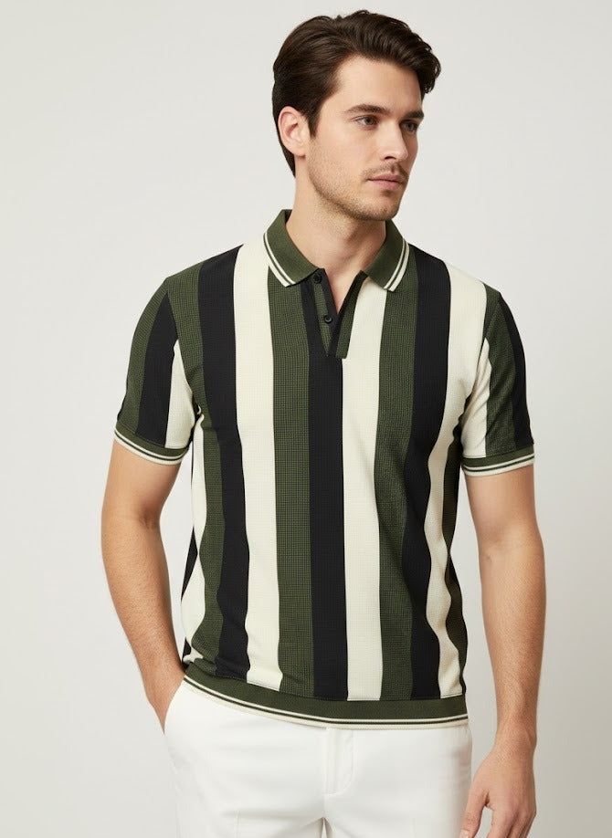 Man wearing a black and white striped polo shirt with white pants on a light gray background