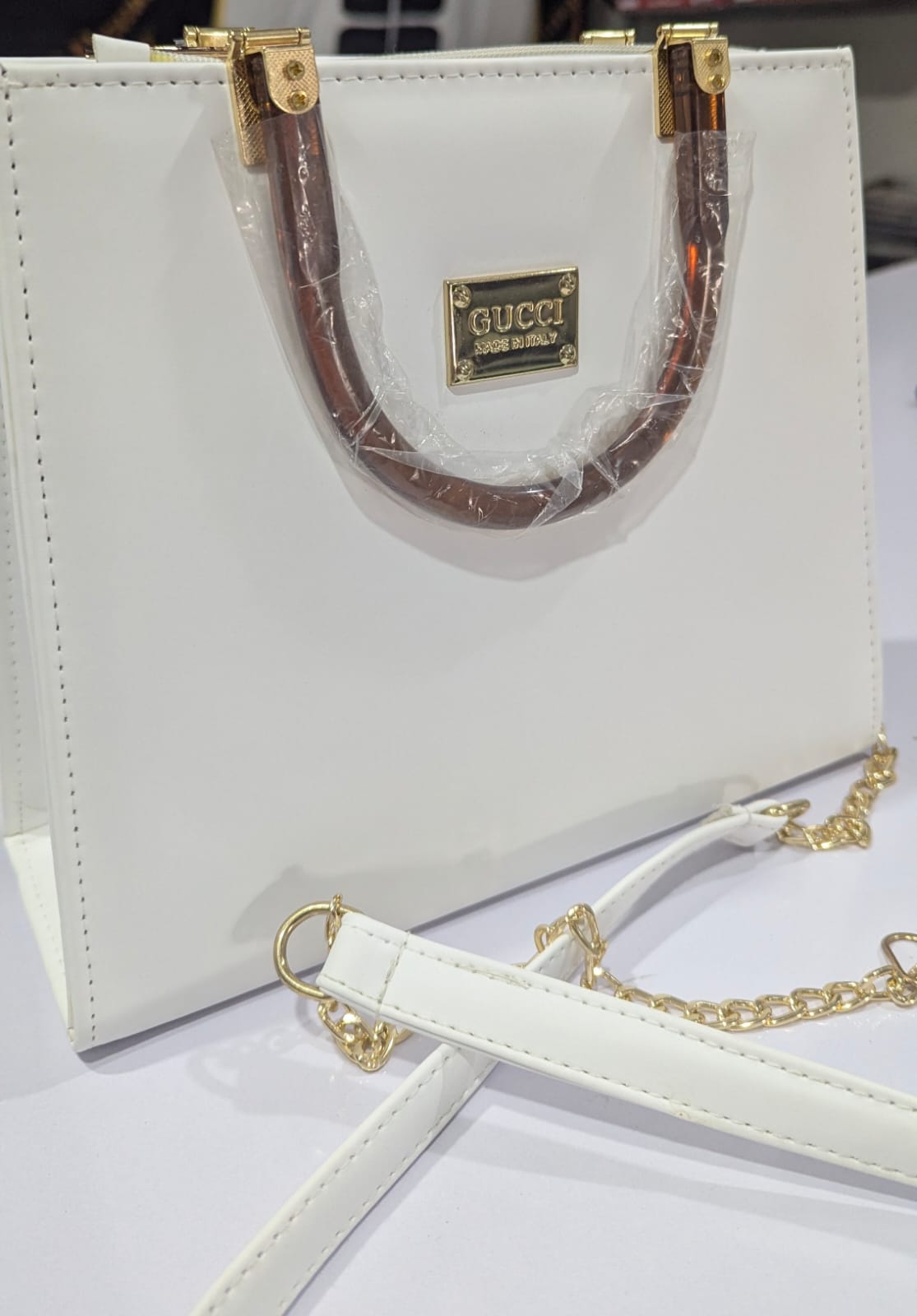 White Gucci handbag with gold accents on a white background