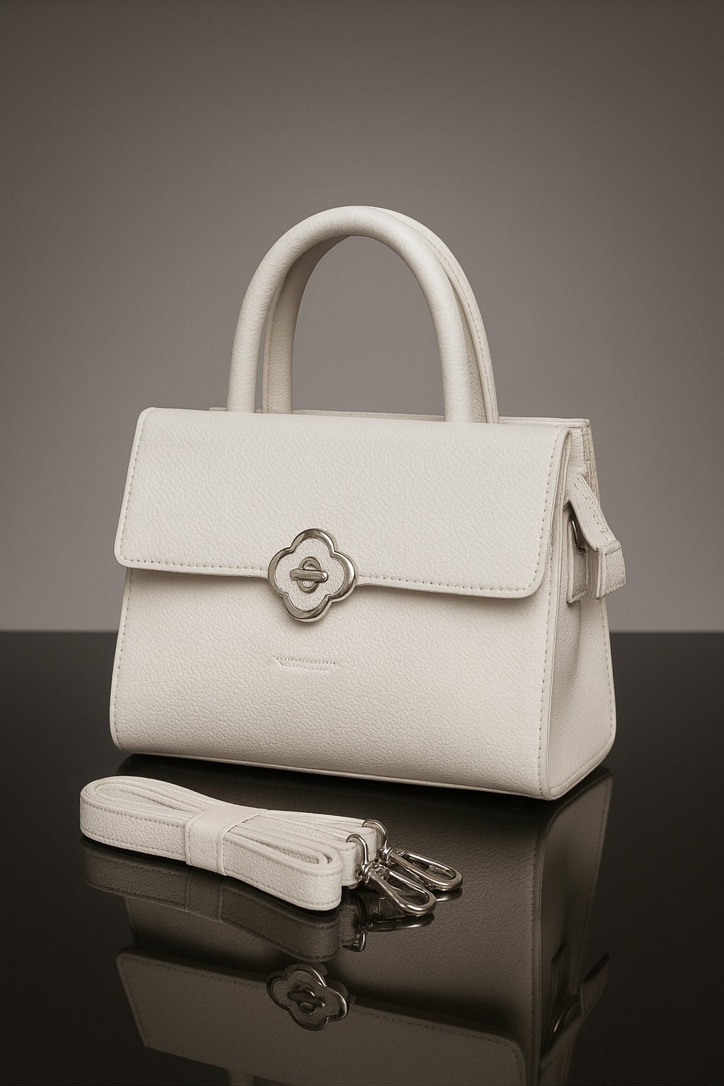 White handbag with a silver clasp on a reflective surface with a gray background