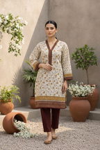 Woman in a floral dress standing outdoors with plants and flowers around