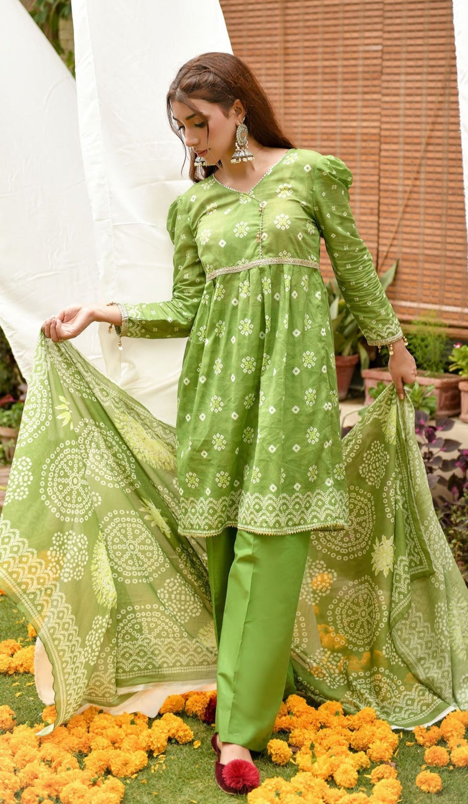 Woman in a green traditional outfit with floral patterns standing on flowers.
