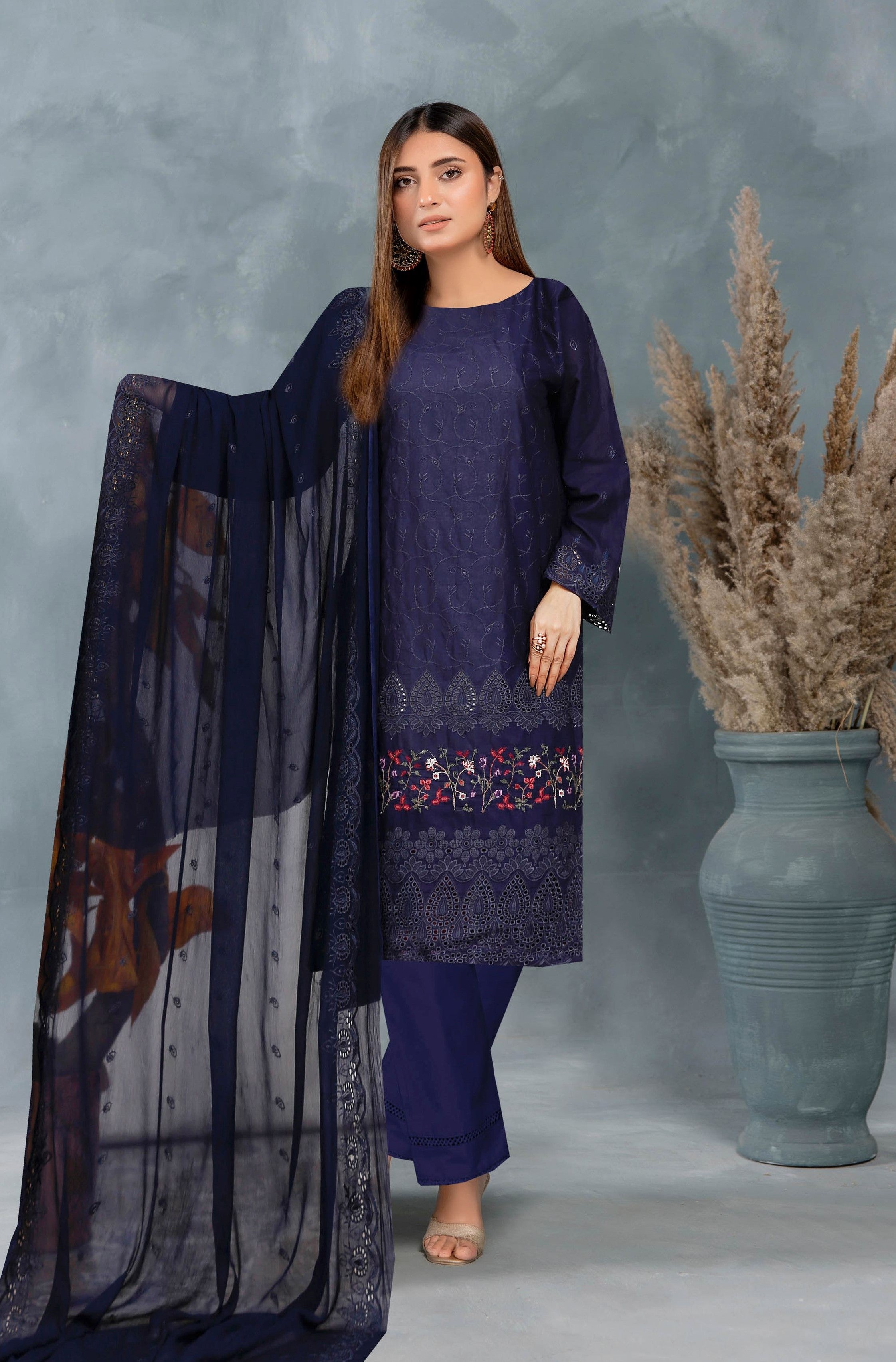 Woman in a navy blue traditional outfit with a sheer dupatta against a gray background