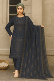 Woman in a navy blue traditional outfit with a matching dupatta against a beige wall.