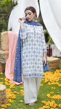 Woman in a patterned outfit standing in a decorated outdoor setting with flowers and fabric.
