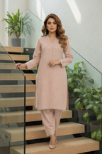 Woman in a peach outfit standing on a staircase with plants in the background