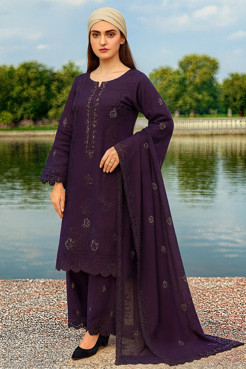 Woman in a purple traditional outfit standing by a lake with trees in the background
