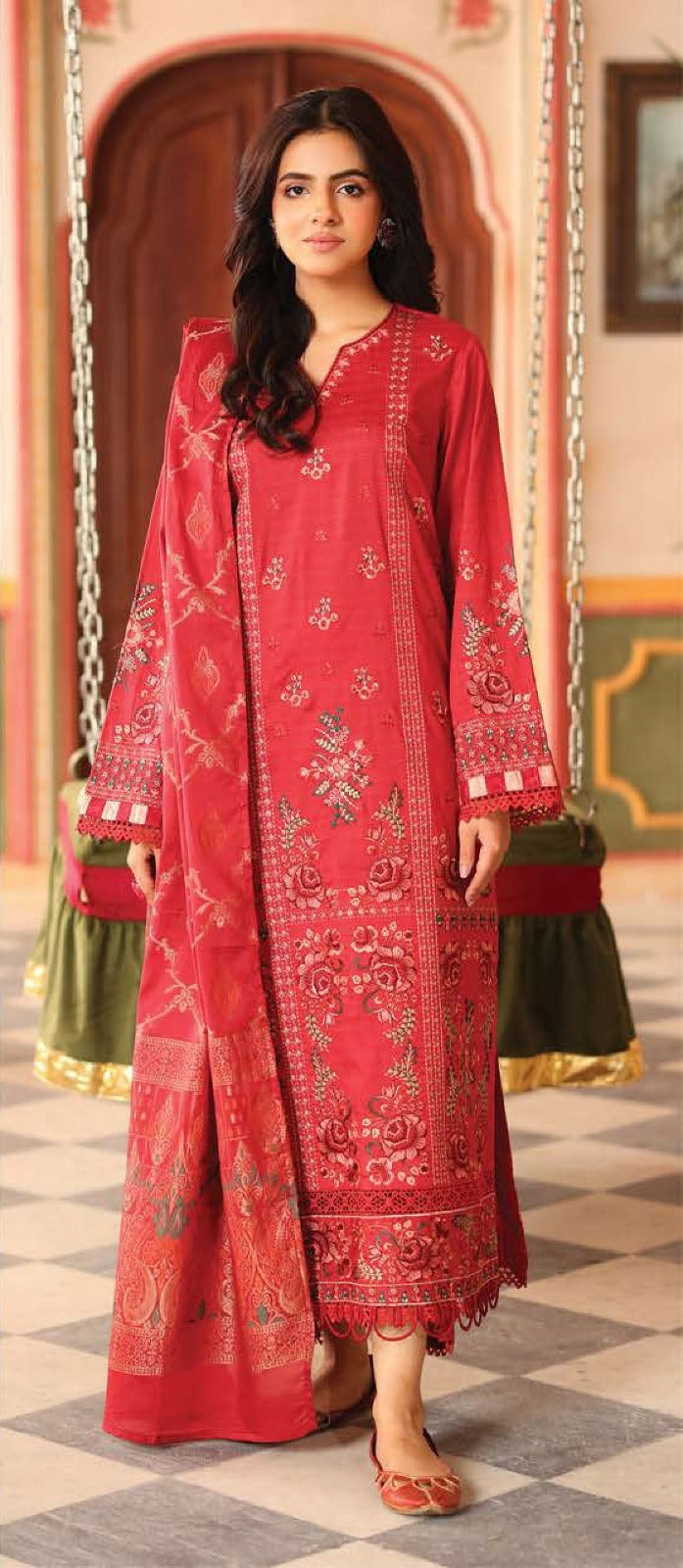 Woman in a red embroidered traditional outfit standing on a checkered floor.