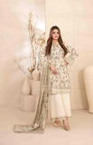 Woman in a white and green printed outfit with a matching dupatta in a minimalistic setting.