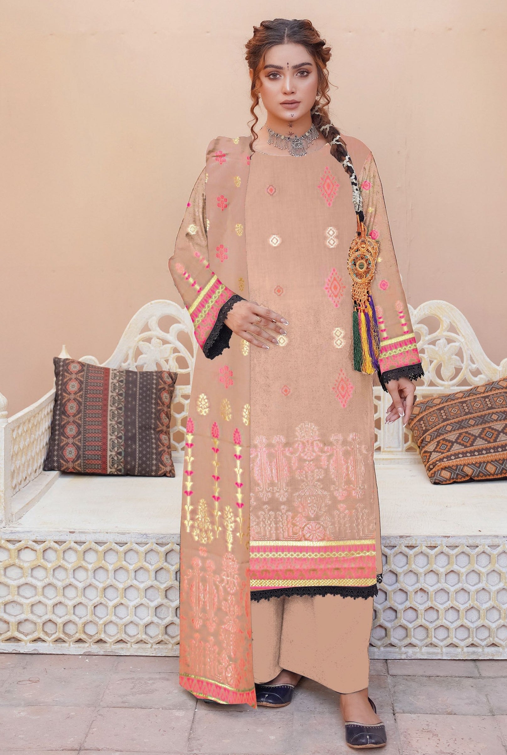 Woman wearing a beige embroidered outfit with a decorative shawl in an outdoor setting.