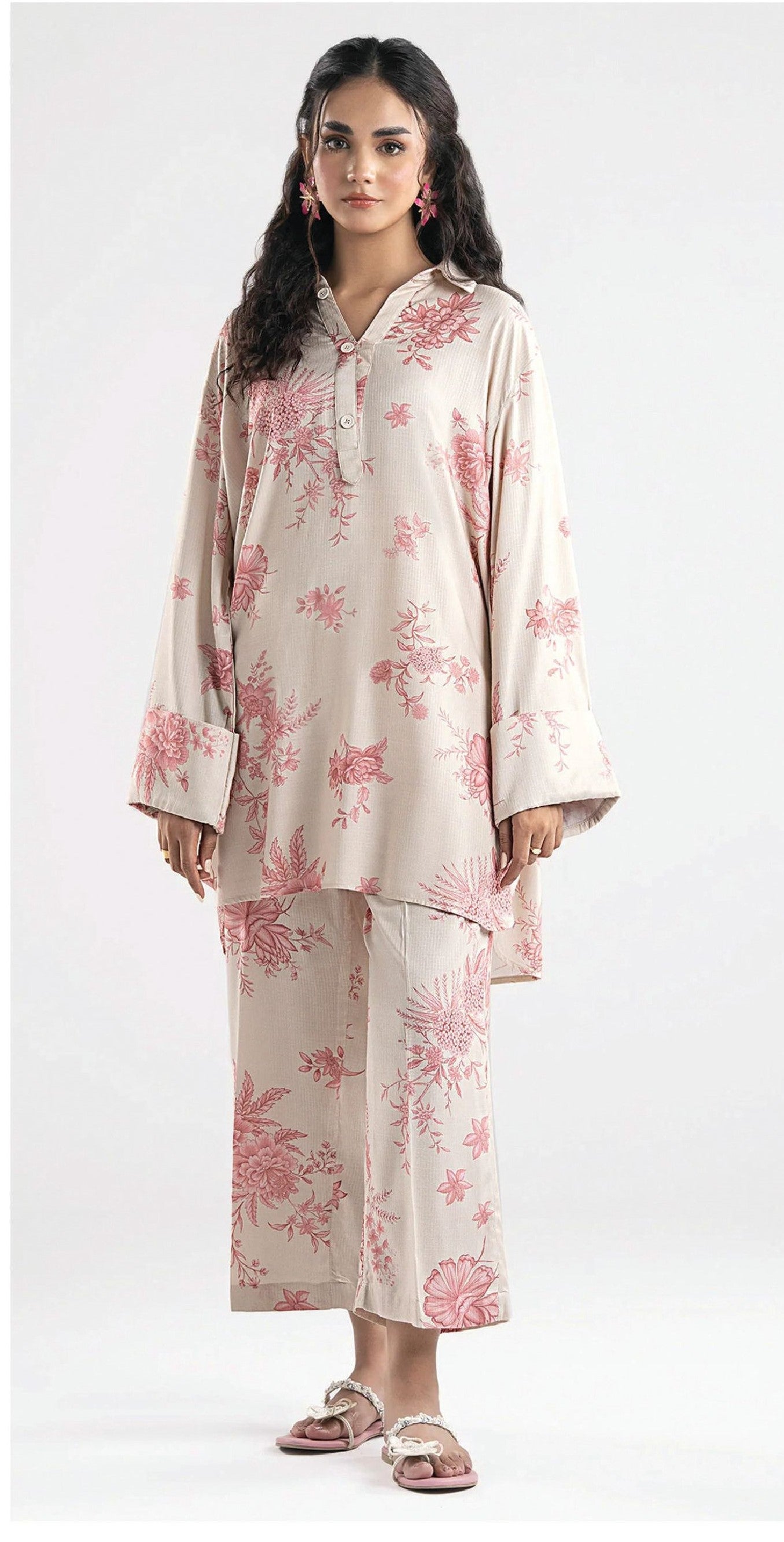 Woman wearing a beige outfit with pink floral patterns on a white background