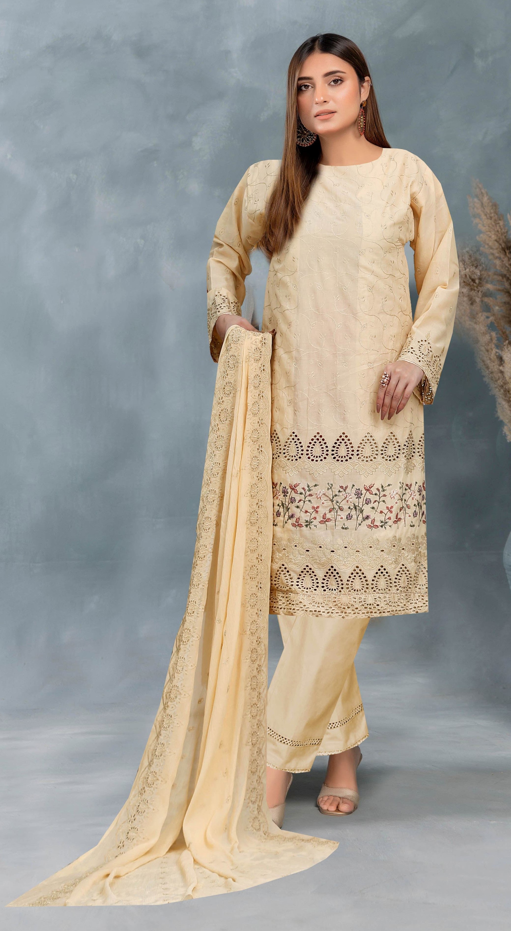 Woman wearing a beige traditional outfit with intricate patterns on a gray background