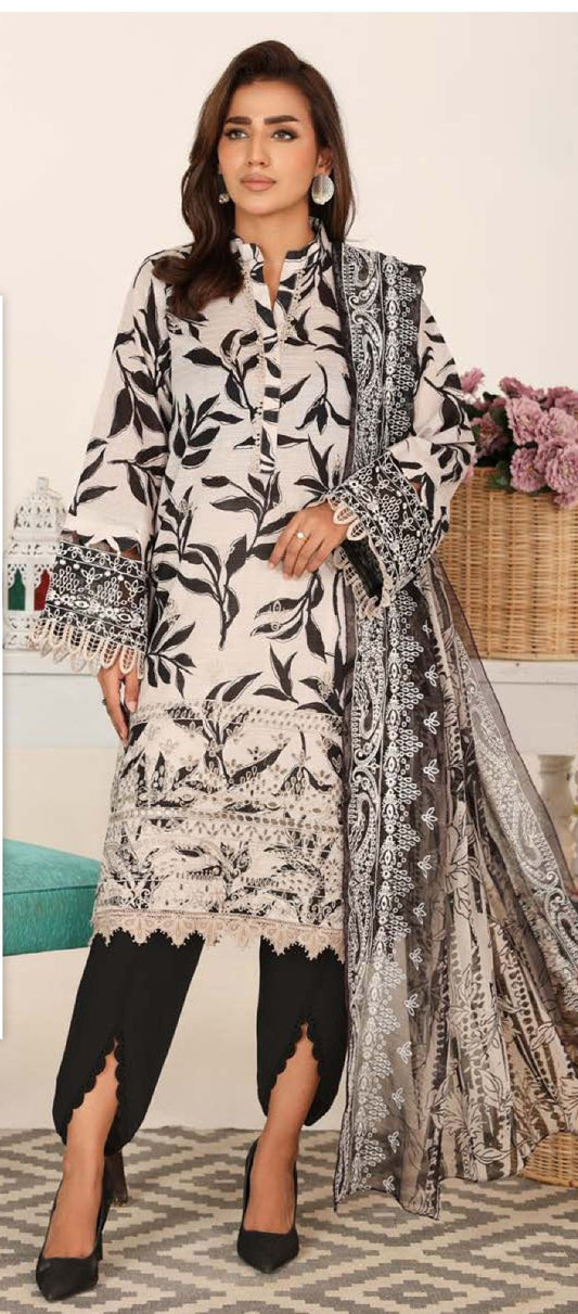 Woman wearing a black and white patterned outfit with a matching shawl in a decorated room.
