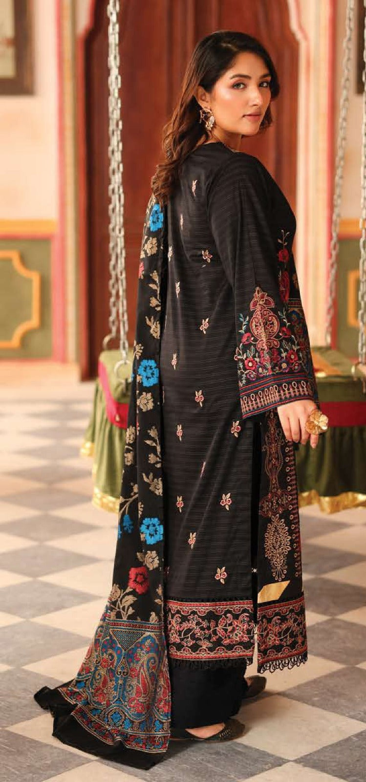 Woman wearing a black embroidered traditional outfit in an indoor setting.