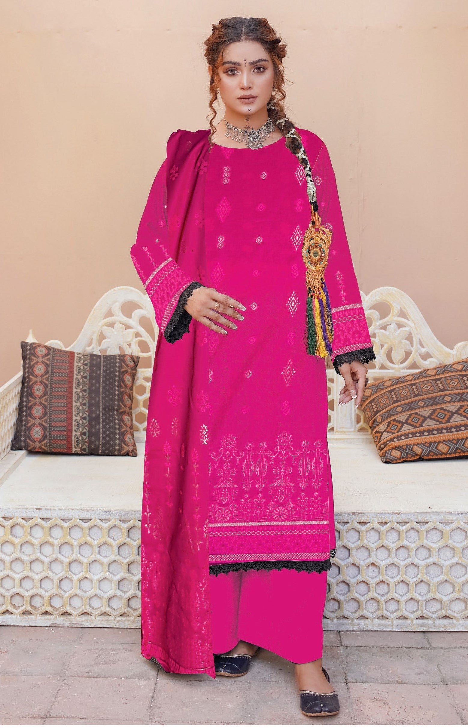 Woman wearing a bright pink traditional outfit with intricate patterns, standing against a neutral background.