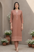 Woman wearing a brown kurta with white flowers and pots in the background