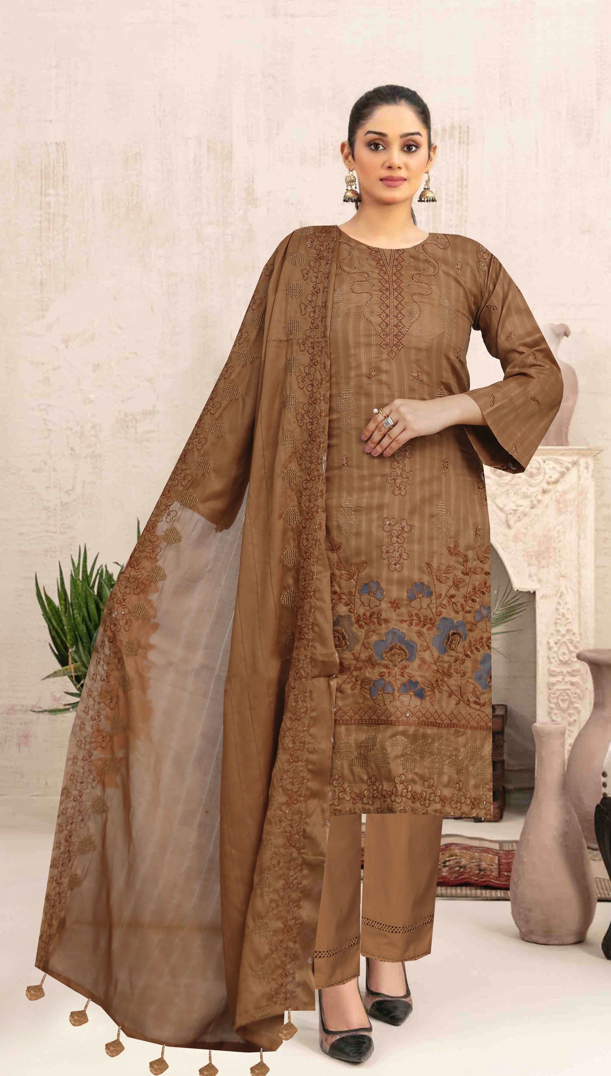 Woman wearing a brown traditional outfit with a matching dupatta in an indoor setting.
