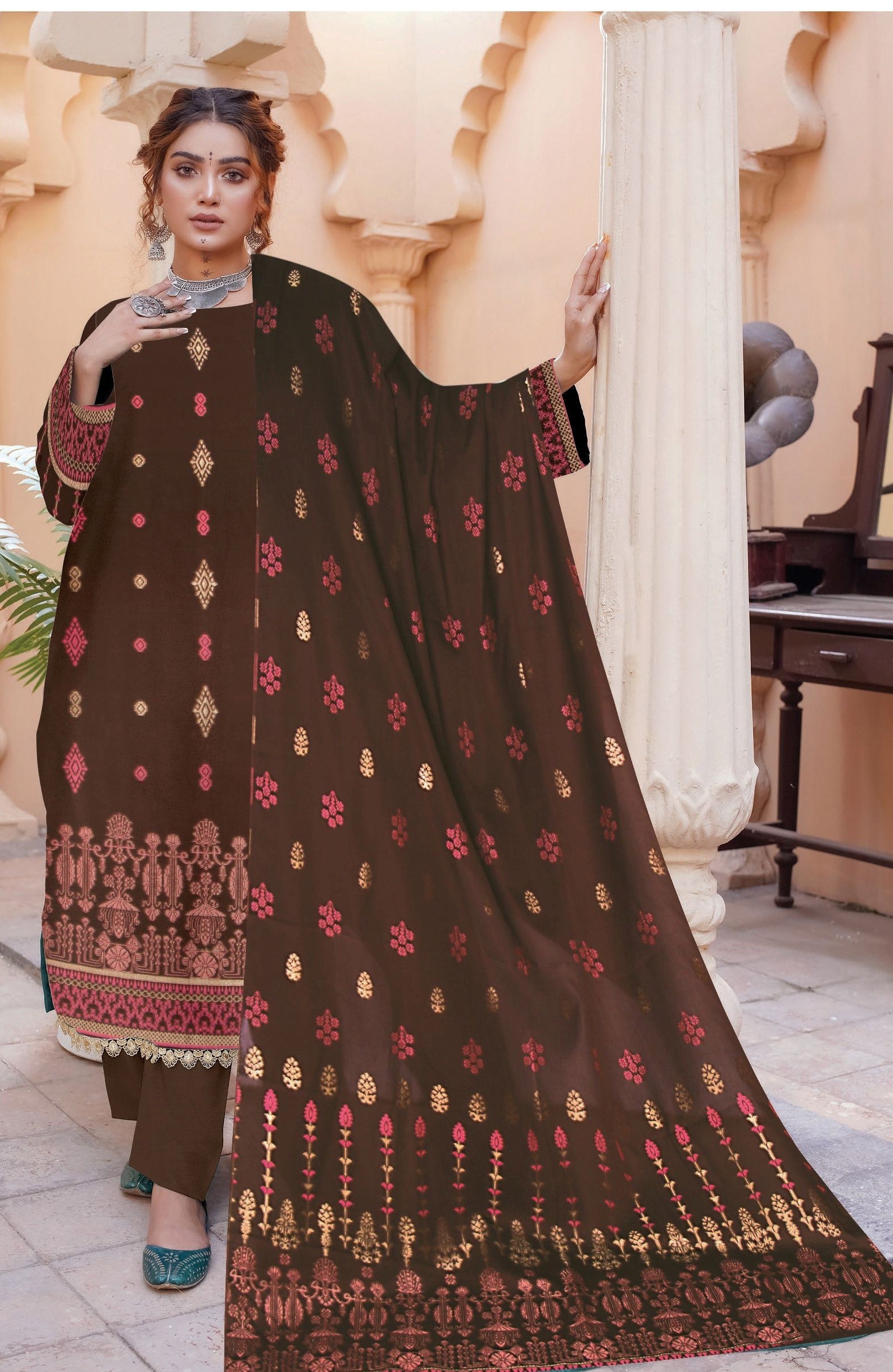 Woman wearing a brown traditional outfit with intricate patterns in an indoor setting.