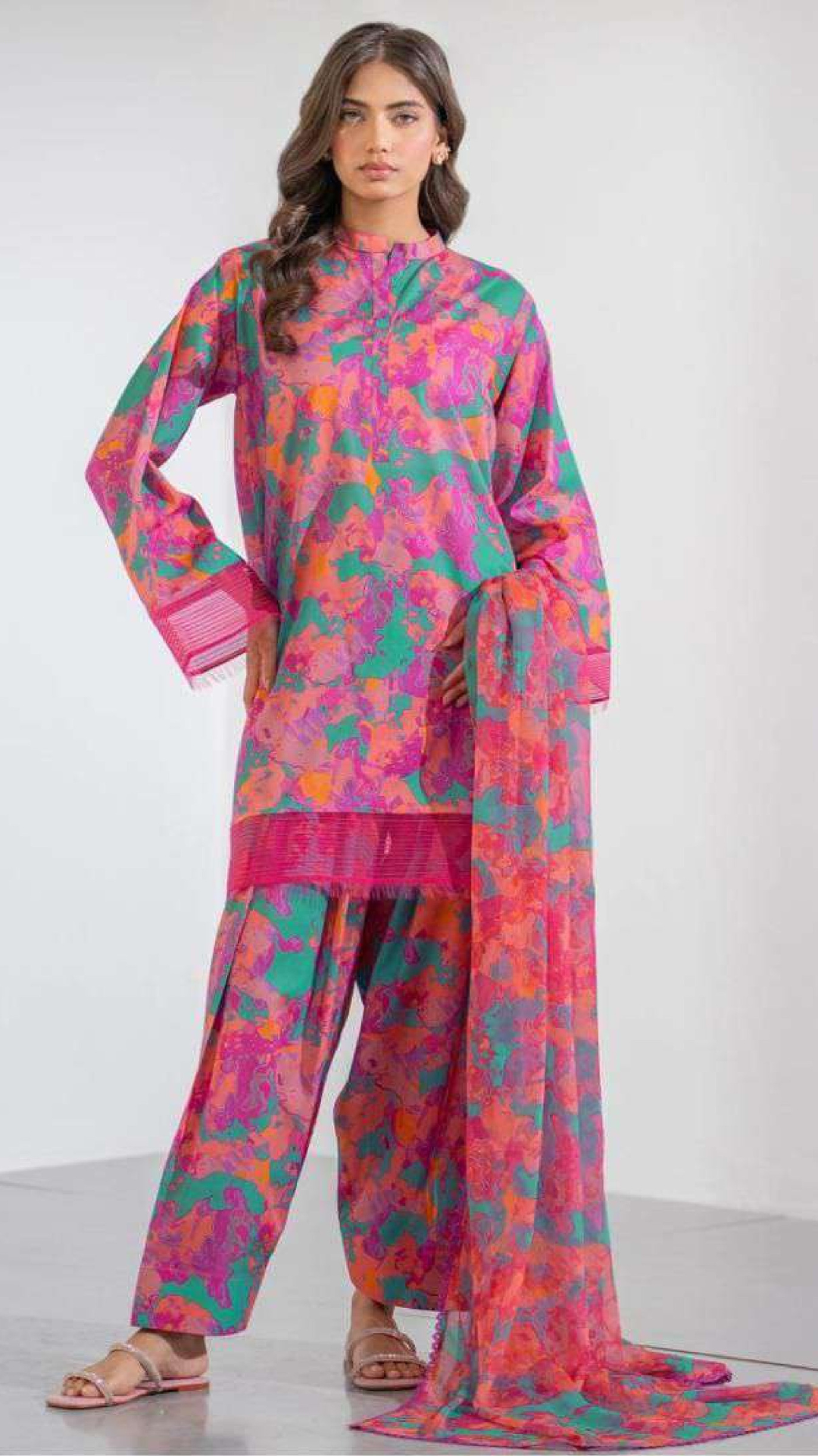 Woman wearing a colorful traditional outfit with a pink and green pattern on a white background