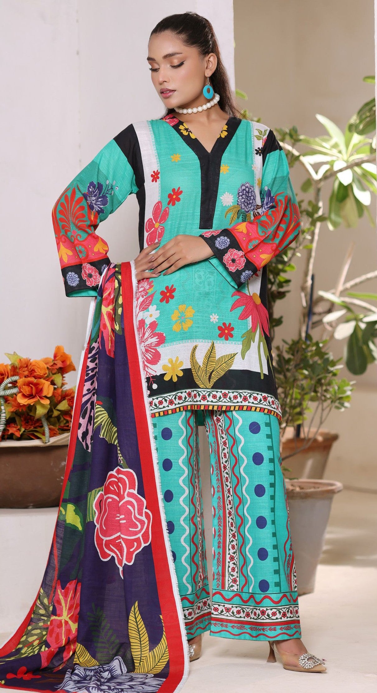 Woman wearing a colorful traditional outfit with floral patterns in a home setting.