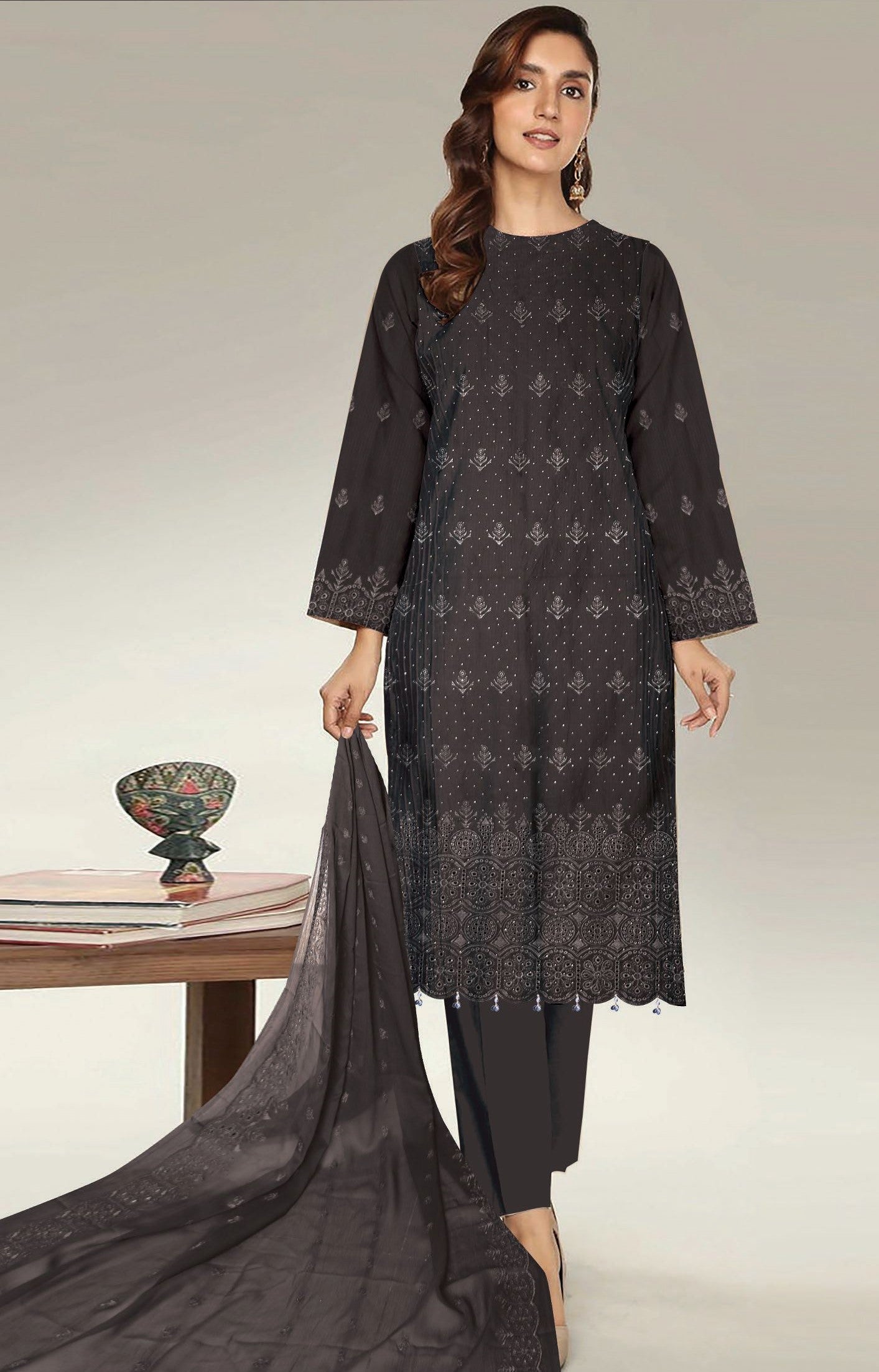 Woman wearing a dark gray embroidered kurta with same trouser, holding a matching dupatta on a light gray background.