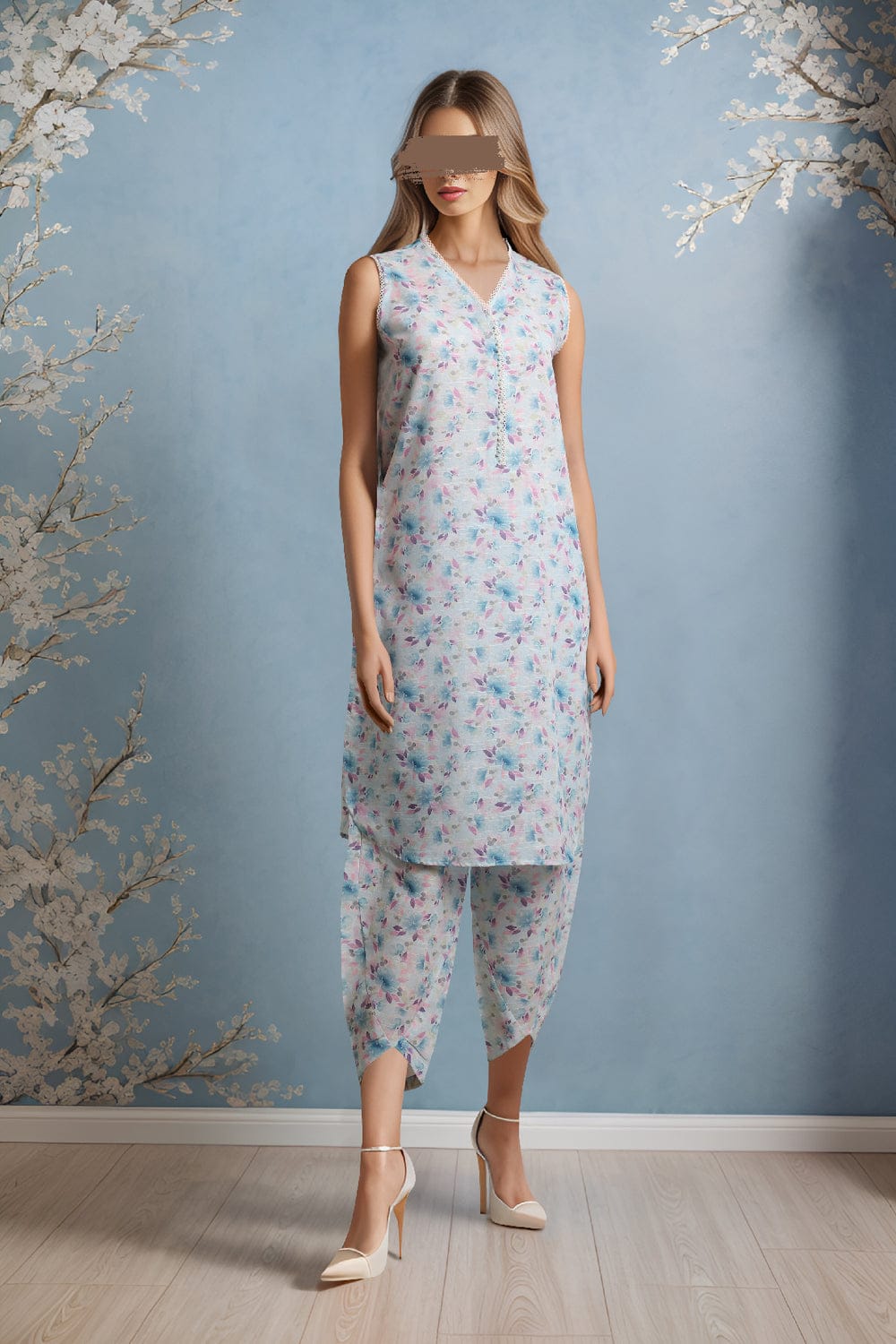 Woman wearing a floral dress and pants set against a blue wall with decorative branches.