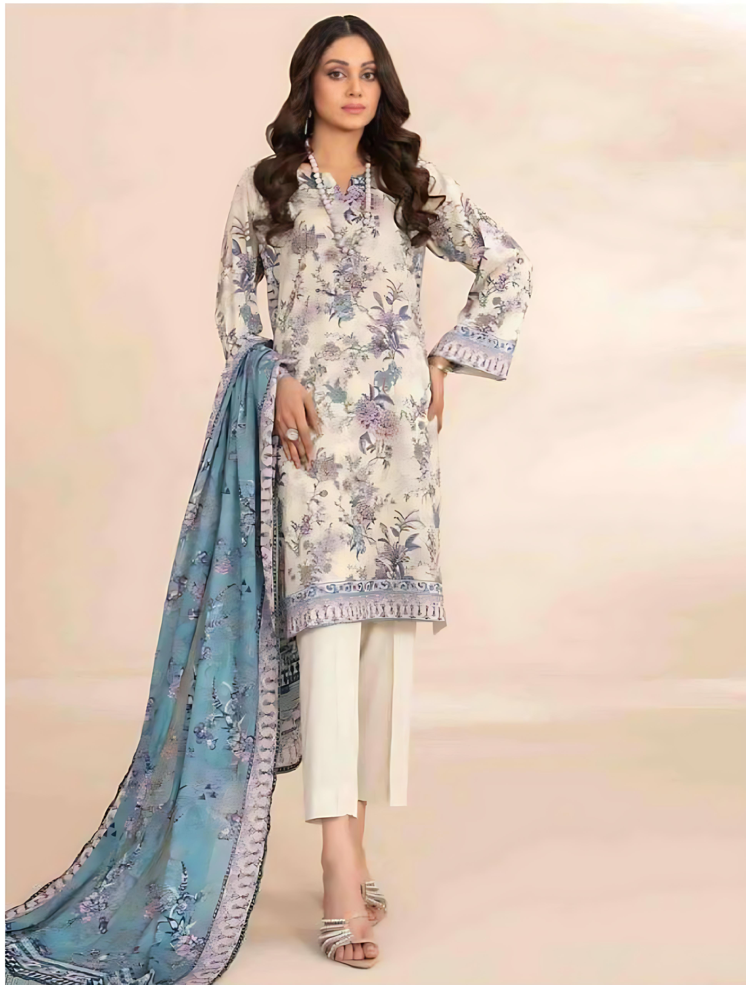 Woman wearing a floral dress with a blue dupatta on a light pink background