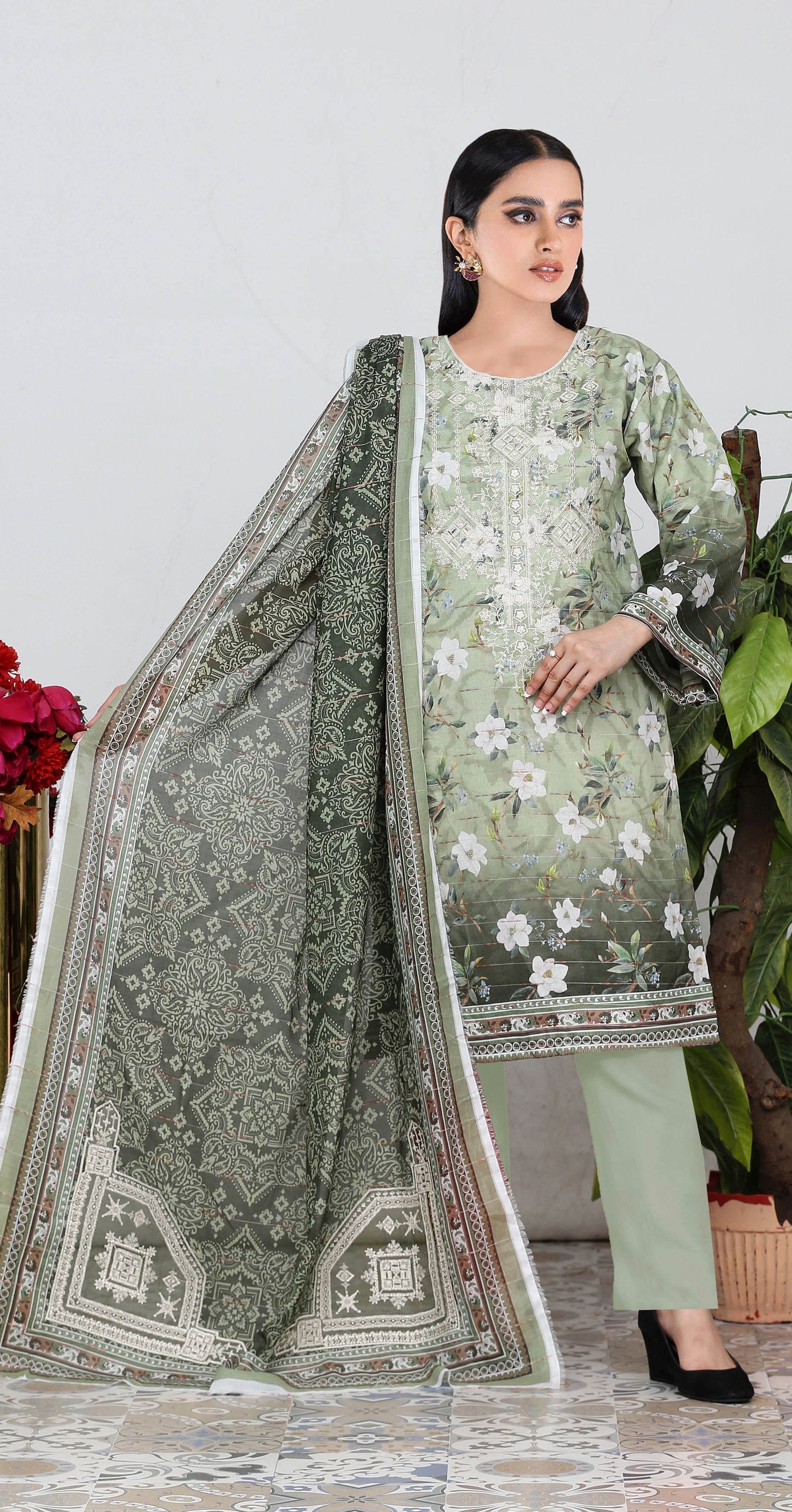Woman wearing a floral dress with a matching dupatta in a room setting.