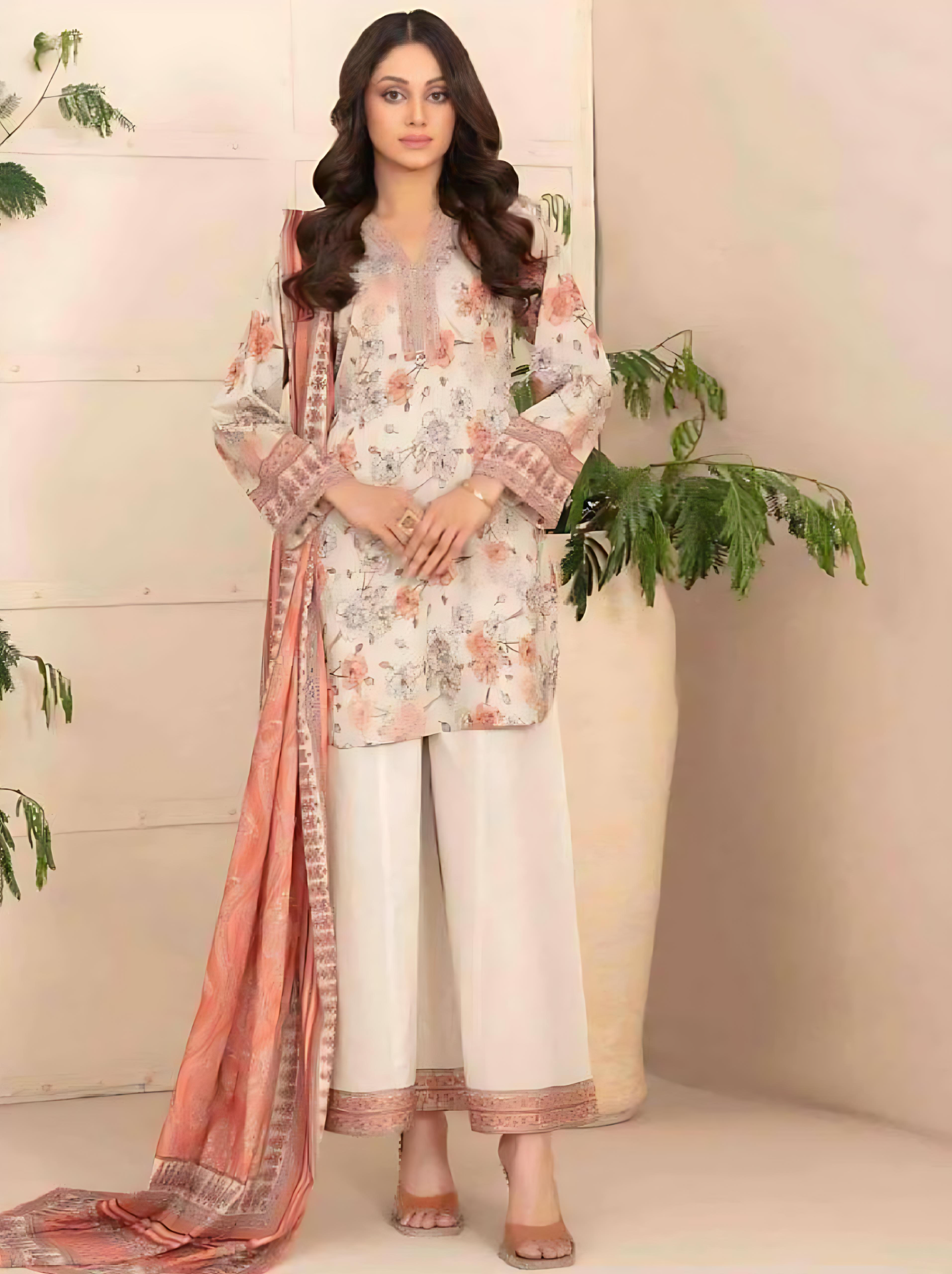 Woman wearing a floral dress with a pink dupatta in a minimalistic setting