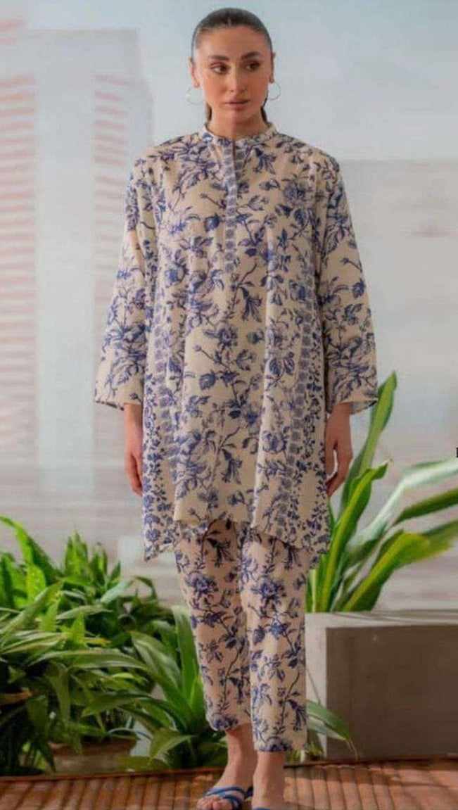 Woman wearing a floral outfit standing indoors with plants in the background