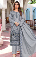 Woman wearing a gray embroidered traditional outfit with a dupatta in an outdoor setting.