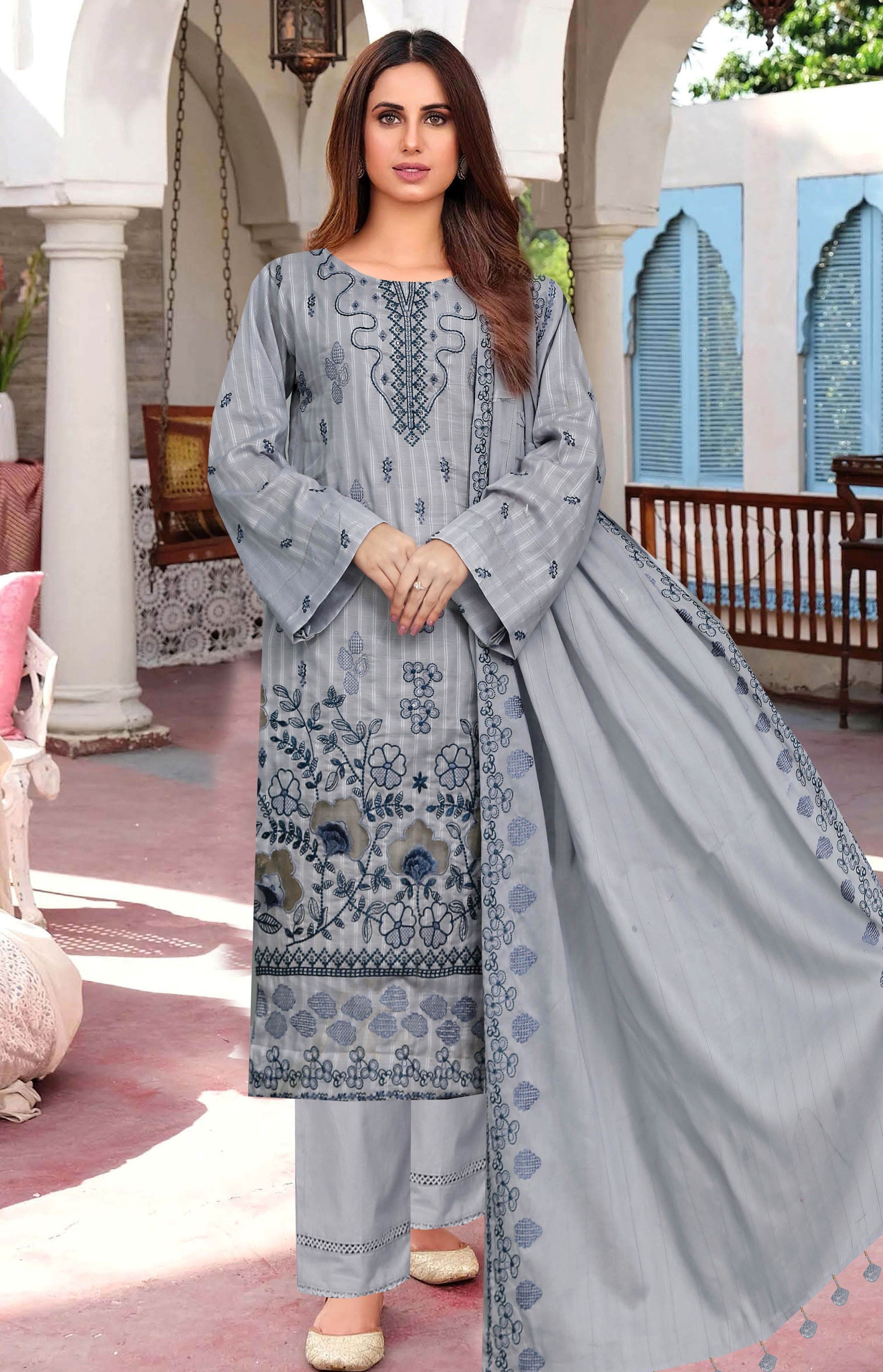 Woman wearing a gray embroidered traditional outfit with a dupatta in an outdoor setting.
