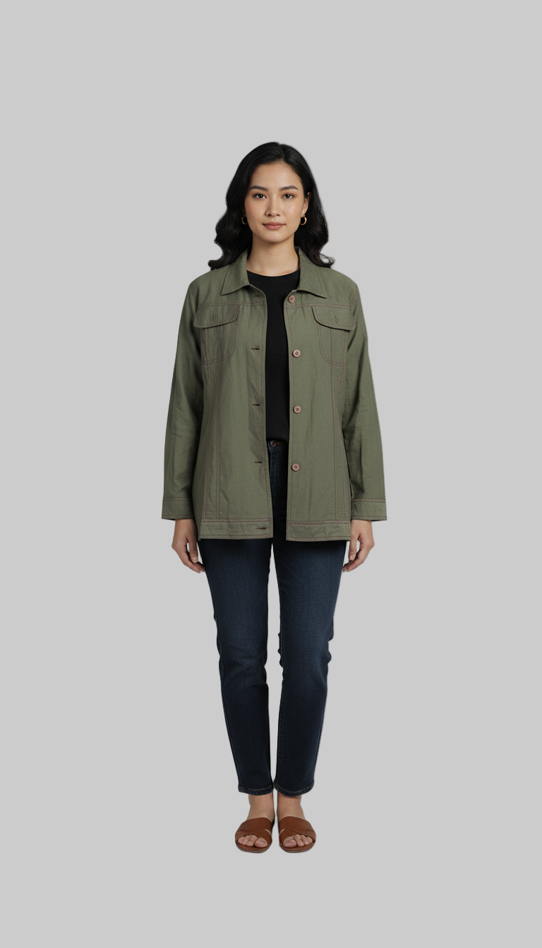 Woman wearing a green jacket and dark jeans on a gray background