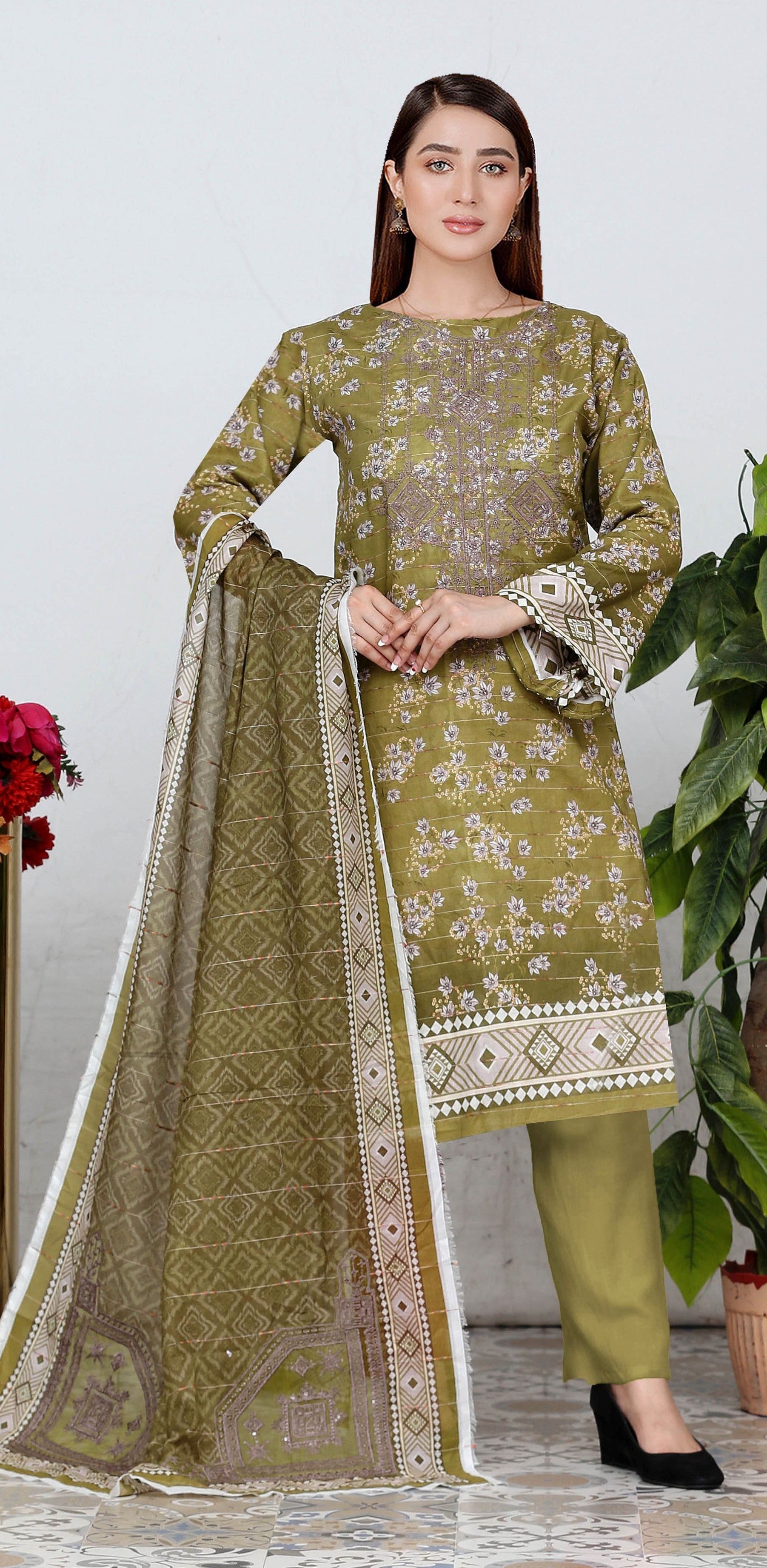 Woman wearing a green embroidered traditional outfit with a white dupatta.