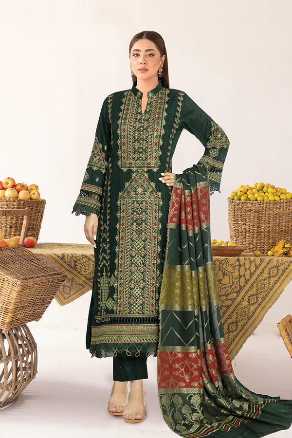 Woman wearing a green embroidered traditional outfit with a patterned dupatta, standing in front of fruit baskets.