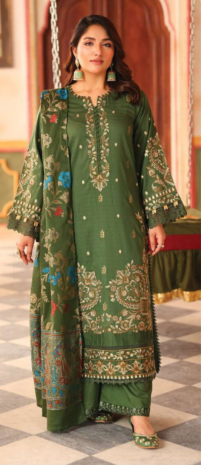 Woman wearing a green embroidered traditional outfit in an indoor setting.